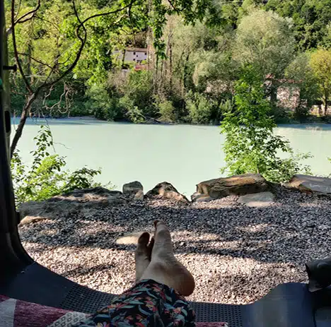 pieds de vanlifeuse dépassant de son van aménagé en bord de rivière